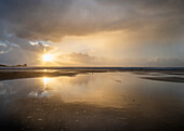 Regenwolken und Spiegelungen am Strand von Rhossili bei Sonnenuntergang mit dem Schiffswrack der Helvetia, Rhossili, Gower, Südwales, Vereinigtes Königreich, Europa