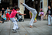 Mitglieder der Mestre Branco Capoeira Escola demonstrieren auf der Straße während der Fiestas von El Pilar in Zaragoza, Aragonien, Spanien