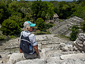 Tourist auf Struktur 142, einer Tempelpyramide in der Nordakropolis in den Maya-Ruinen im Yaxha-Nakun-Naranjo-Nationalpark, Guatemala. Struktur 144 ist rechts zu sehen.