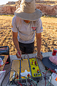 A technician demonstrates electrical triggers or controllers for fireworks launchers for a fireworks show in a field in Utah.