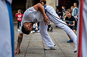 Mitglieder der Mestre Branco Capoeira Escola demonstrieren auf der Straße während der Fiestas de El Pilar in Zaragoza, Aragonien, Spanien