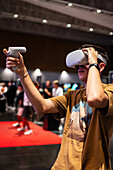 Teenager spielt mit dem Meta Quest 2 All-in-One VR-Headset während des ZGamer, einem Festival für Videospiele, digitale Unterhaltung, Brettspiele und YouTuber während der El Pilar Fiestas in Zaragoza, Aragon, Spanien