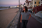 Woman looking at the sea from Promenade Jacques Thibaud boardwalk in front of the Grande Plage beach of Saint Jean de Luz,fishing town at the mouth of the Nivelle river,in southwest France’s Basque country