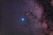 Ein Ausschnitt aus einem weiten Feld in Aquila, mit dem hellen blau-weißen Stern Altair in der Mitte, dem roten Stern Tarazed darüber und dem schwächeren Stern des Trios, Alshain, darunter.