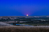 The rising of the August 1,2023 "supermoon" Full Moon,over the Bow River and valley,on the Siksika Nation lands,in the heart of the traditional Blackfoot Confederacy territory in southern Alberta,Canada.