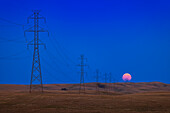 The Full Moon of July 31,2023 rising at the end of a long line of high tension towers across the prairie near Milo,Alberta. Some smoke in the air made the rising Moon even redder than normal,making it look like an eclipsed Moon. This night the alignment of the rising point of the Full Moon coincided with the angle of the powerlines off to the southeast at 135° azimuth.