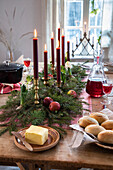 Festive wooden table with red candles, fir branches and apples