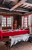 Rustic dining room with wooden beamed ceiling and red table setting