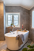 Modern bathroom with freestanding bathtub and Christmas decorations on a wooden shelf