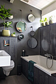 Modern bathroom with dark tiles, mirror decoration and plant arrangement