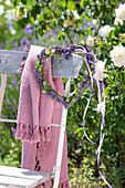 Lavender heart wreath and pink scarf hanging on garden chair in summer garden