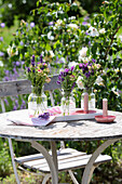 Round wooden table in the garden with bouquets of flowers in glass vases and candles