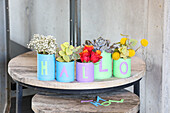 Colourful tin cans with flowers result in "HELLO" lettering on wooden table