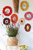 Round, colourful photo frame with floral decoration in front of white wall