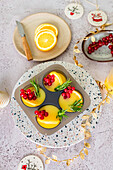 Ice cube tray filled with orange juice, garnished with redcurrants and rosemary