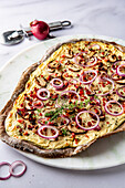 Linseed flour tarte flambée with red onions, mushrooms and bacon