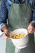 Mann hält Sieb mit frisch gekochter Pasta
