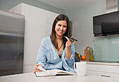 Young woman in kitchen talking on smartphone