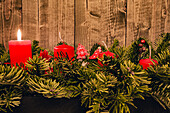Four red candles on an Advent arrangement, one candle burning