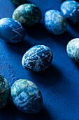 Blue Easter eggs on a blue background with blooming cherry blossoms