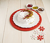Donut cake with white icing, pistachios, pomegranate seeds and chocolate
