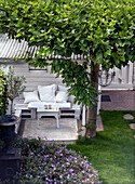 Garden seating area with white wooden bench surrounded by green plants