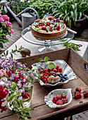 Summer cake with fresh berries and kiwi on a garden terrace