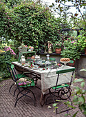 Richly laid garden table with green metal chairs