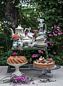 Coffee table in the garden with china crockery, bundt cake and fruit cake