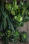 Fresh tatsoi, black cabbage, pak choi and kale on a wooden table