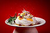 Mini pavlova with apricot jam and whipped cream, garnished with pomegranate seeds and rosemary