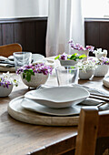 Spring dining table with white and purple flowers in ceramic bowls