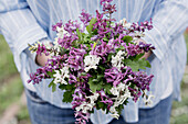 Frau hält Blumenstrauß aus Lerchensporn (Corydalis) in Weiß und Lila