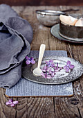 Vintage zinc plate with candied purple flowers on a rustic wooden table