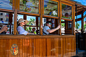 Touristen in der historischen Straßenbahn im Dorfzentrum von Soller. Die Straßenbahn verkehrt auf einer Strecke von 5 km zwischen dem Bahnhof im Dorf Soller und dem Puerto de Soller, Soller, Mallorca, Balearen, Spanien, Mittelmeer, Europa