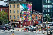 Dreistöckiges, von der Sonne beleuchtetes Wandbild von Mutter Teresa und Mahatma Gandhi des brasilianischen Straßenkünstlers Eduardo Kobra an der Seite eines Gebäudes in Chelsea, Manhattan