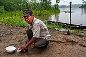 Ein Bewohner des am Fluss gelegenen Dorfes Timicuro I schärft ein Messer vor seinem Haus. Iqutios am peruanischen Amazonas, Loreto, Peru