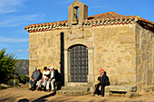 Vier Rentner sitzen auf den Steinbänken der Einsiedelei El Consuelo in der Stadt Santa Cruz de Pinares, Provinz Ávila