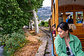 Asiatischer Tourist in der historischen Straßenbahn am Hafen von Soller. Die Straßenbahn verkehrt auf einer Strecke von 5 km vom Bahnhof im Dorf Soller zum Puerto de Soller, Soller Mallorca, Balearen, Spanien, Mittelmeer, Europa