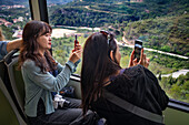 Asiatische Touristen im Inneren der Cremallera-Zahnradbahn, die den Berg Montserrat hinauffährt, Monistrol de Montserrat, Barcelona, Spanien