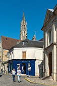 Frankreich, Oise, Senlis, Frauen gehen auf einer gepflasterten Straße mit einer Buchhandlung und einer Kirche im Hintergrund