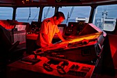 France, French Southern and Antarctic Territories (TAAF), Marion Dufresne II (supply ship of the TAAF), At the bridge, Alexandre LE BOUCHER (Lieutenant Commissioner) is at the chart table at dusk, The red lights allow to do not be dazzled so as not to degrade night vision