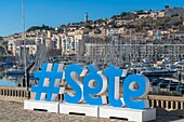 Frankreich, Herault, Sete, Saint-Louis Mole, Skulptur eines Hashtags, der die Stadt Sete darstellt, mit einem Leuchtturm im Hintergrund