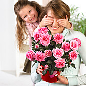 Girl surprising mother with bouquet of roses