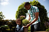 Father and child holding shrub