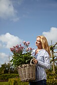 Frau hält Korb mit Aquilegia