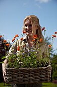 Woman holding basket with Geum and Myosotis