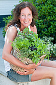 Woman holding basket with mixed herbs