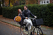 Fahrrad fahrendes Paar mit Blumen in der Hand