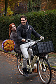 Fahrrad fahrendes Paar mit Blumen in der Hand